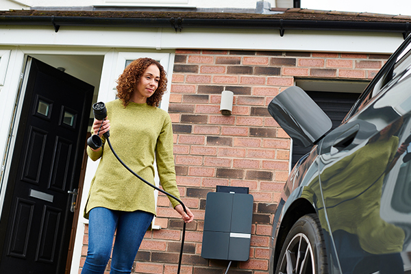 Woman charging electric vehicle at home